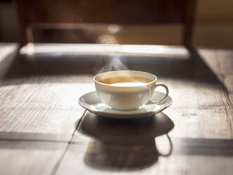 Cup of hot green tea on wooden surface - HAMF00837