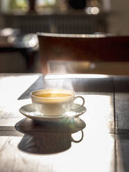 Cup of hot green tea on wooden surface - HAMF00838