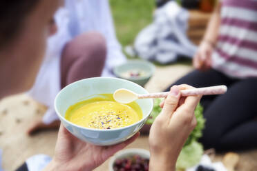 Woman with food bowl sitting by friends - CVF01654