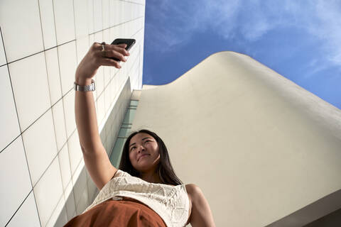 Young woman taking selfie with mobile phone on sunny day stock photo