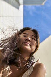 Asiatische Frau vor einem Gebäude an einem sonnigen Tag - VEGF03937