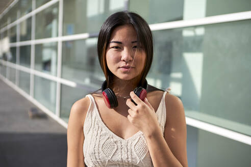 Beautiful woman with headphones around neck on sunny day - VEGF03954