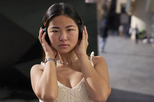 Young woman listening music through headphones outdoors - VEGF03955