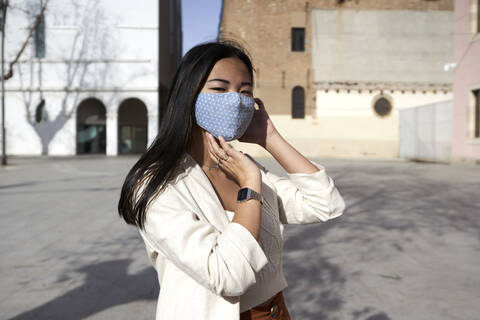 Young woman with protective face mask on footpath during sunny day stock photo