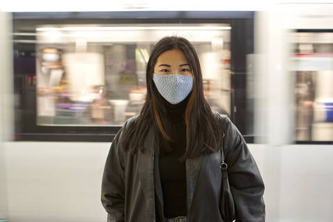 Young woman during pandemic with moving train in background stock photo