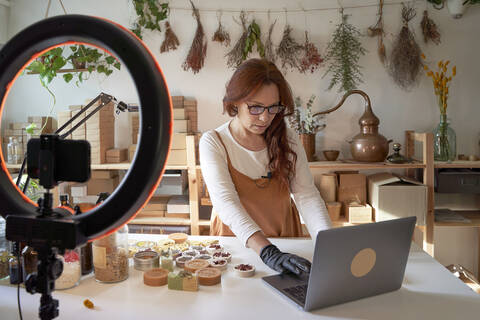 Bloggerin mit Laptop bei der Vorbereitung eines Video-Tutorials auf einem Workshop, lizenzfreies Stockfoto