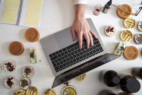 Die Hand einer Unternehmerin tippt auf einem Laptop über dem Tisch - VEGF03990