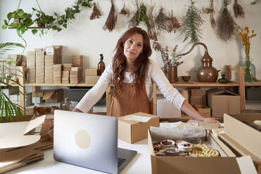 Smiling female entrepreneur leaning on table at workshop - VEGF03999