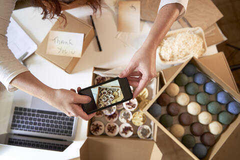 Woman photographing handmade soaps through smart phone at workshop stock photo