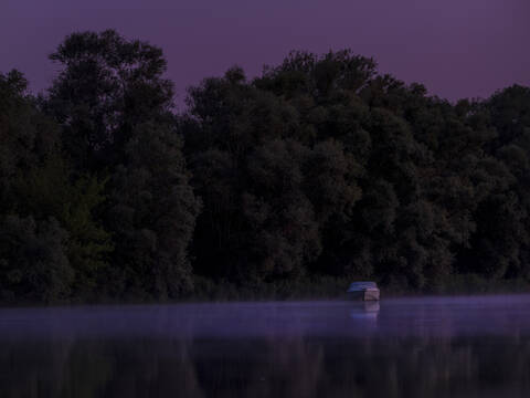 Lone motorboat floating in Saone river at purple night stock photo
