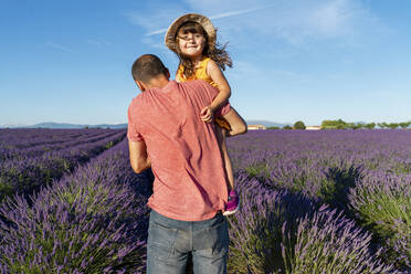 Father carrying baby daughter in vast lavender field during summer - GEMF04698