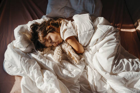 Sweet little girl sleeping in motor home with stuffed rabbit toy - GEMF04714