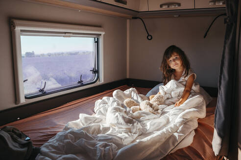 Portrait of little girl lying in bed inside motor home - GEMF04717