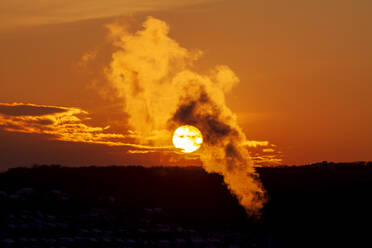 Dampf aus dem Heizkraftwerk schwebt gegen den Himmel bei stimmungsvollem Sonnenuntergang - NDF01254