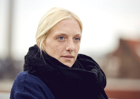 Thoughtful young woman in scarf at parking garage looking away stock photo