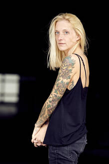 Tattooed woman with hands clasped at parking garage - UKOF00128