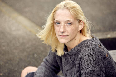 Blond woman with freckles sitting at parking garage - UKOF00142