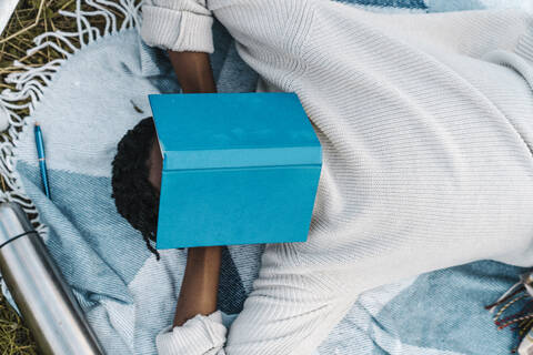 Young man taking nap while covering his face with a book stock photo
