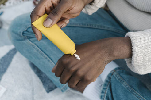 Junger Mann trägt Handcreme durch eine Tube auf - BOYF01892