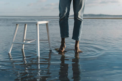 Mann mit weißem Hocker am Wasser stehend gegen den Himmel - BOYF01912