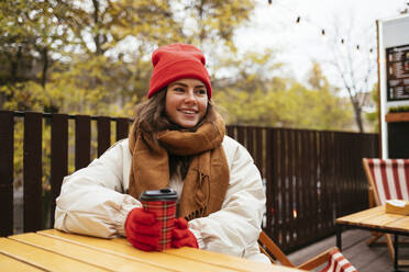 Junge Frau in warmer Kleidung bei einem Kaffee in einem Straßencafé - OYF00314