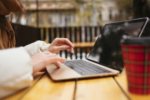 Woman using laptop while sitting at sidewalk cafe stock photo