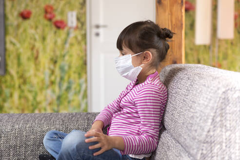 Child sitting on couch in face mask - DRF01764