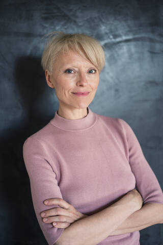 Lächelnde Frau an der Wand stehend, lizenzfreies Stockfoto