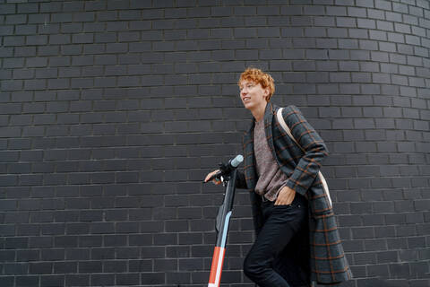 Man with electric push scooter by wall stock photo