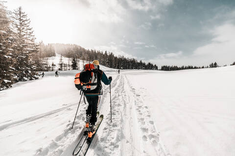 Active senior man skiing on snow covered land during vacation stock photo