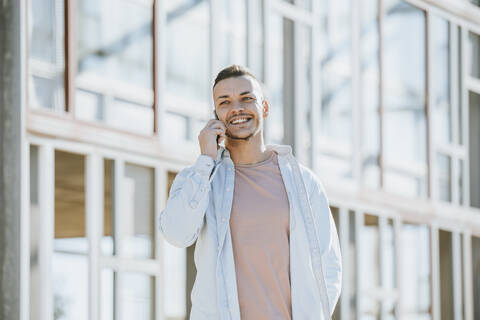 Lächelnder Mann, der im Freien steht und mit seinem Handy spricht, lizenzfreies Stockfoto