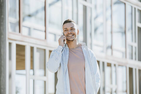Smiling man talking on mobile phone while standing outdoors stock photo