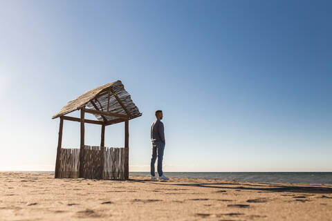 Man looking at sea view while standing on beach during sunny day stock photo