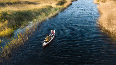 Junges Paar, das mit dem Kanu auf einem Fluss im Wald unterwegs ist - SBOF02679