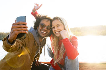 Mann macht Selfie mit Frau durch Handy, während er im Kanu auf dem Fluss sitzt - SBOF02697
