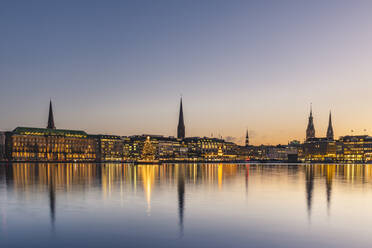 Germany, Hamburg, City architecture reflecting in Binnenalster lake at dusk - KEBF01782