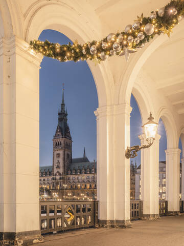 Deutschland, Hamburg, Alsterarkaden mit Weihnachtsdekoration und Blick auf das Rathaus in der Dämmerung, lizenzfreies Stockfoto