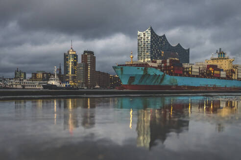 Deutschland, Hamburg, Anlegertheater, Elbphilharmonie und sich im Wasser spiegelndes Containerschiff - KEBF01812