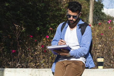 Junger männlicher Unternehmer mit Dokumenten im Park an einem sonnigen Tag, lizenzfreies Stockfoto