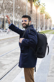 Male professional waving while standing at station - PNAF00760