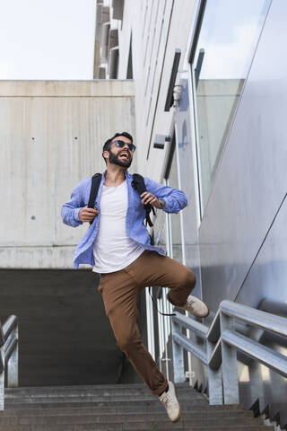 Fröhlicher junger Berufstätiger, der auf einer Treppe springt, lizenzfreies Stockfoto