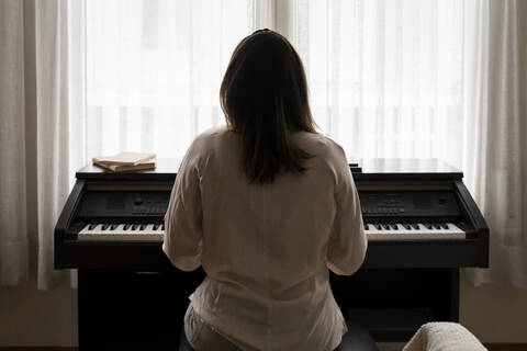 Young woman playing piano at home stock photo