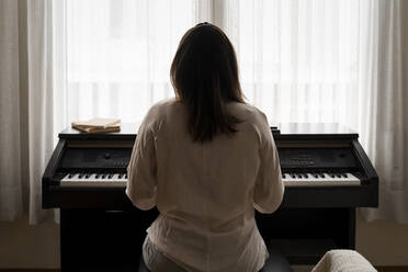 Junge Frau spielt zu Hause Klavier - AFVF08235
