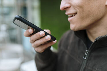 Close up of man sending a voice message with his smartphone - OCAF00641