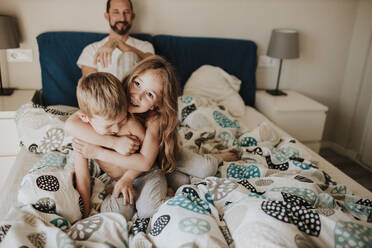 Father watching girl and boy playing at bed - GMLF00995