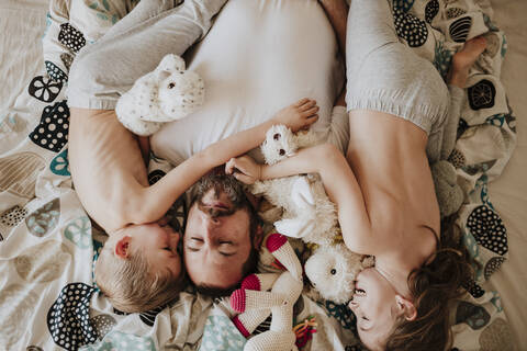 Vater schläft mit Tochter und Sohn auf dem Bett zu Hause, lizenzfreies Stockfoto