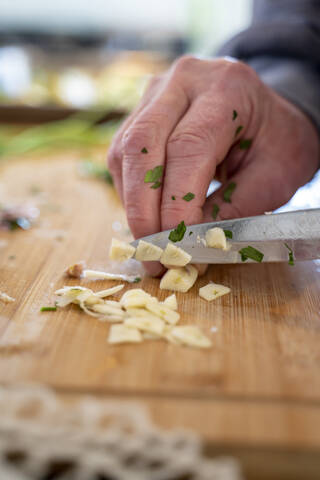 Älterer Mann schneidet Knoblauch auf einem Schneidebrett, lizenzfreies Stockfoto