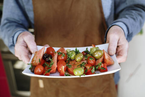 Senior man with apron holding tray of tomatoes stock photo