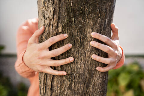 Woman embracing tree trunk in garden stock photo