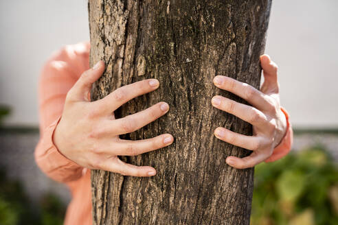 Woman embracing tree trunk in garden - AFVF08269